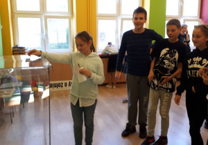 Uczniowie wrzucają wypełnione karty do głosowania do urny.