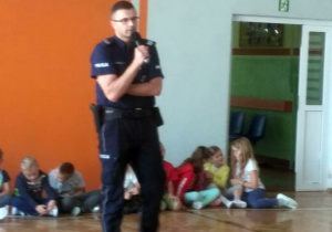 Spotkanie policjanta z uczniami na sali gimnastycznej.