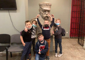 Pięcioro uczniów przed popiersiem marszałka Józefa Piłsudskiego.