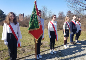 Sztandar szkoły reperentowany przez troje uczniów w czasie uroczystości pod pomnikiem Armii "Łódź"