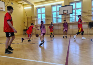 Sala gimnastyczna. Uczniowie rozgrywają mecz koszykówki.