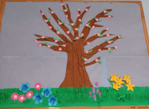 Wiosenne drzewo wykonane z kolorowego papieru, zdobiące tablicę korkową w sali świetlicowej.