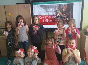 Dzieci pokazują wykonane przez siebie biało-czerwone kotyliony w kształcie kwiatków.