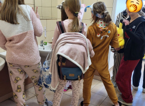 Uczennice przebywające w toalecie, ubrane w pluszowe piżamy.