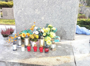 Pomnik cmentarny ozdobiony kwiatami i zniczami.