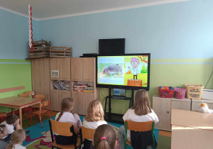 Uczniowie oglądają na tablicy multimedialnej film edukacyjny o jeżach.