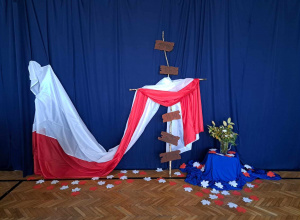 Dekoracja przygotowana na apel z okazji Święta Niepodległości-krzyż przepleciony biało-czerwoną flagą.
