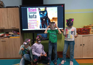 Uczniowie w wykonanych przez siebie papierowych maskach czarnego kota.