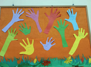 Ręce wycięte z kolorowego papieru, na których wypisane są prawa dziecka.