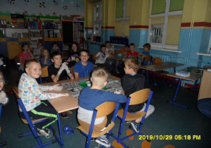 Uczniowie siedzą w grupach.