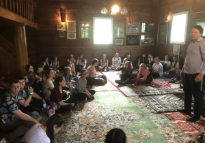 Dzieci słuchają imama o historii i życiu Tatarów w Polsce w meczecie w Kruszynianach