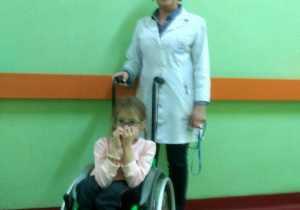 Pielęgniarka z dziewczynką na wózku inwalidzkim.